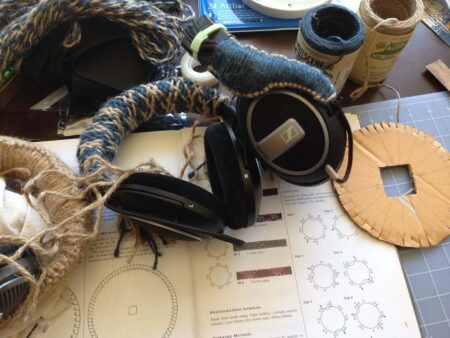 Headphones wrapped in blue and brown twine on a workbench.