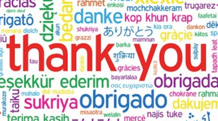 Brightly coloured words in various colours and sizes. The words in question are different ways to say " Thank you" in various different languages.
