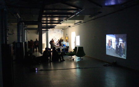 A few people looking at projected images in a dark exhibition space.