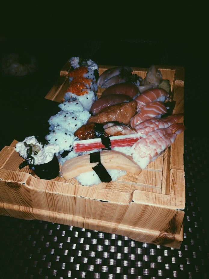 A large wooden tray filled with various types of sushi.