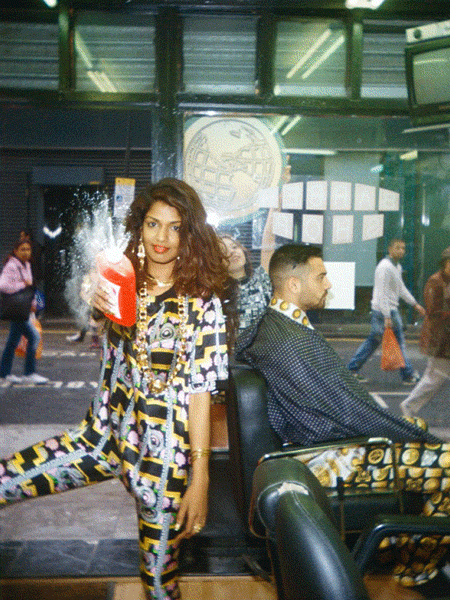 A moving image ( or GIF) of recording artist M.I.A standing in a busy street whilst spraying talcum powder at the camera.