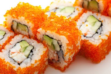 Pieces of sushi which are coated in bright orange fish eggs.