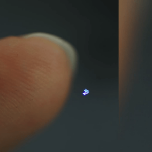 A close up of a persons finger tip. Just at the tip of the finger is a very small image of a flying Fairy which is neon blue in colour.