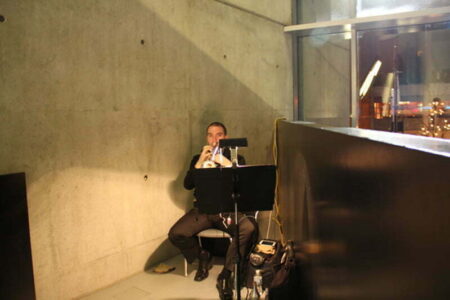 A person playing the trumpet in a small concrete room.