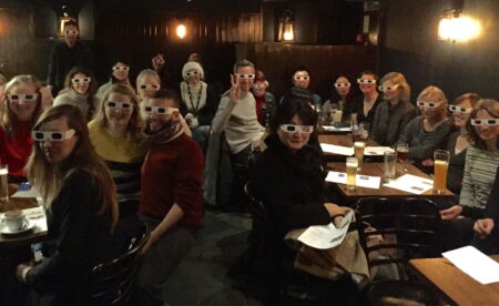 Small audience of people,all wearing 3d glasses.