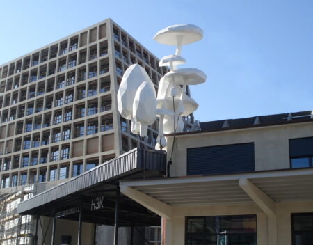 Large white man made mushroom like shapes " growing" on top of a concrete building.