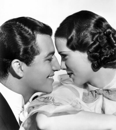 Black and white photo of two 1930's style movie stars gazing into each others eyes.