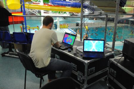 A person controlling visual effects at a swimming pool in Dundee.