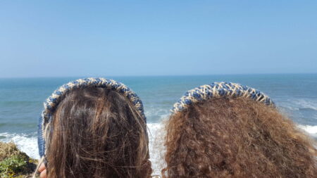Two people wearing specially made headphones whilst looking at the sea.
