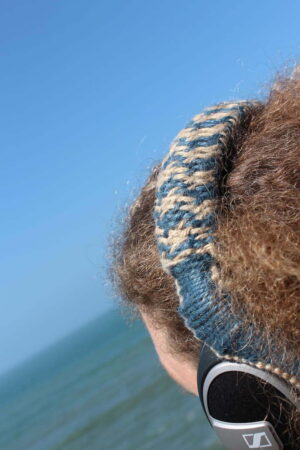 A person wearing specially made headphones whilst looking at the sea.