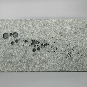 Grey coloured stone slab with splashes of oil on the surface.