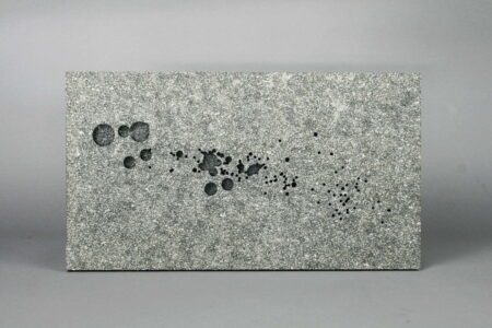 Grey coloured stone slab with splashes of oil on the surface.