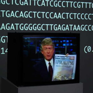A black television monitor sits on a grey plinth. The image on the monitor is of a person holding a Daily Mail newspaper with the headline "Apocalypse".
