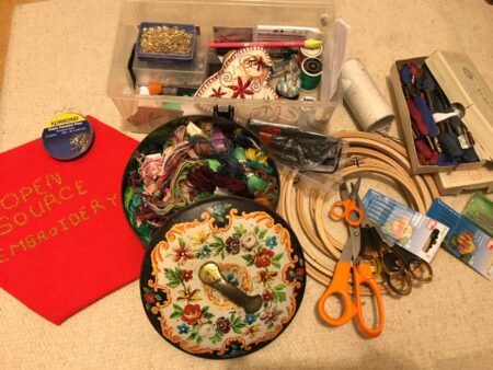 Various embroidery implements including needles,scissors,embroidery rings and a box of thread.