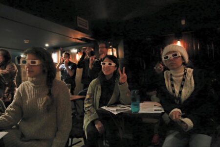 Audience members in a dark room wearing 3d glasses.