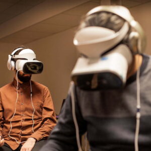 Three people sitting in a room wearing white VR head sets.