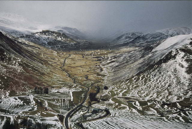Aerial view of part of the Cateran Trial. In the centre of snow capped hills is a long winding road.