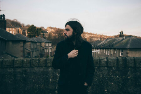 Andrew Wasylyk standing by a wall. In the background is a housing estate.