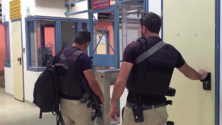 Two security guards with guns at a security checkpoint.