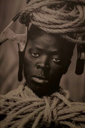 A person with rope coiled around the top of the head and from the neck down.