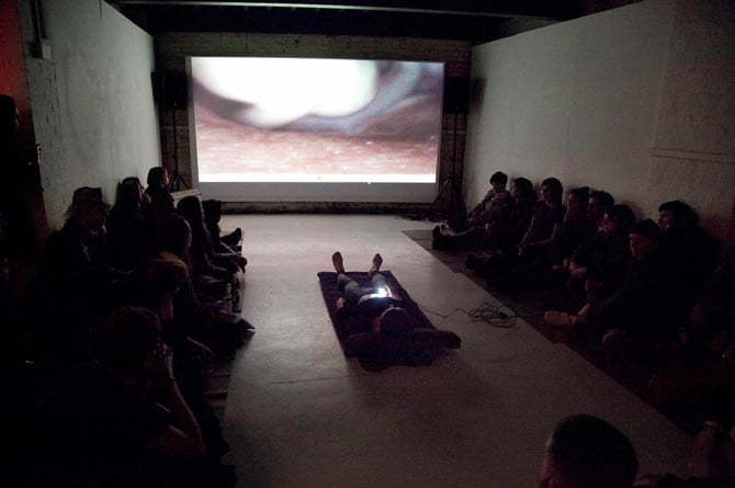 A group of people in a room looking at a projector screen.