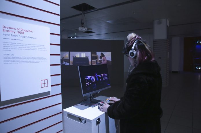 A person wearing headphones playing a game on a small monitor.