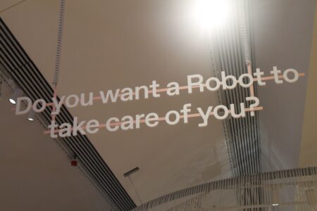 The words " Do you want a Robot to take care of you?" suspended in the air in a white room.