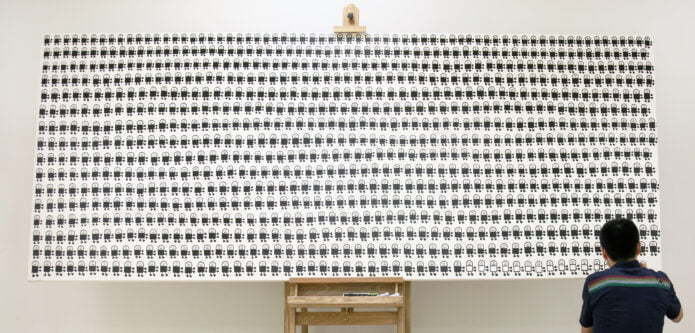 Person standing in front of large board full of black and white illustrations.