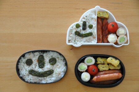 Three small rice dishes. Two of which have smiley faces on them.One dish is shaped like a car.