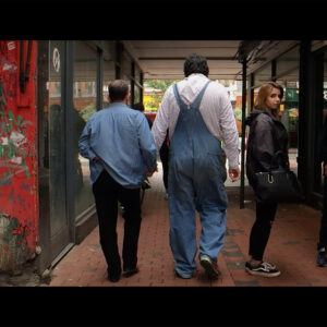 Film still from Walking Holding by Rosanna Cade.Two people holding hands and walking down a shopping arcade.