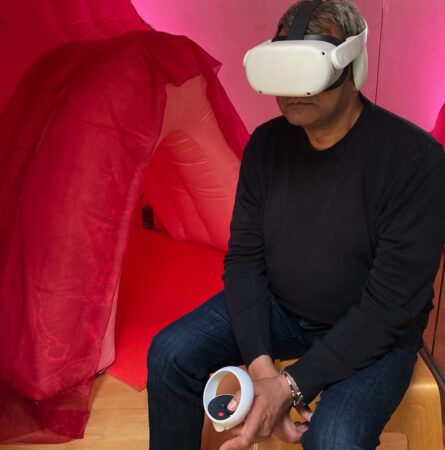 INTER_her by Camille Baker. Audience member sitting in a pink room wearing a VR head set.