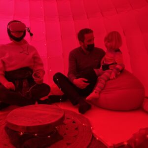 INTER_her by Camille Baker. Audience sitting on bean bags, in red light. One audience member wearing VR.
