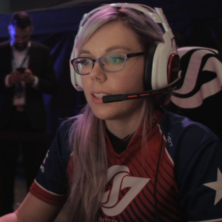 A photo of Stephanie Harvey, a professional gamer. She is looking at a screen whilst talking through a headset.